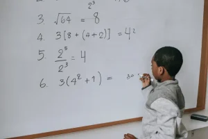 Numeracy - A young boy solving a maths problem on a whiteboard