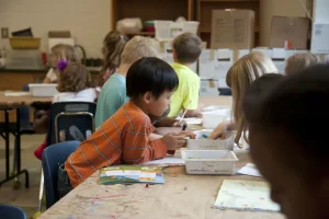 A group of children colouring at their desks within the classroom
