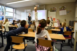 A class with a student raising her hand to answer a question