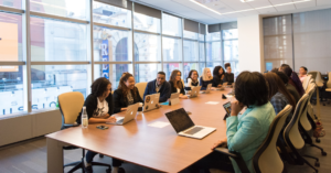 A group of people sat at a conference table together in a large meeting room