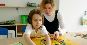 A female teacher helping a young student with an art project