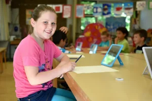 A young female student writing next to an ipad