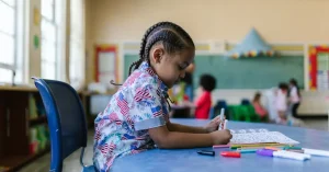 A young child sat at her desk in the classroom working