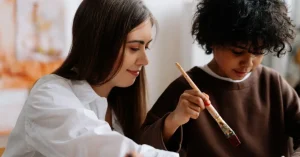 A teacher with a pupil who's painting