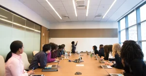A woman presenting to a boardroom full of adult learners