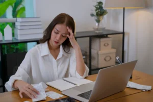 Woman calculating bills on a desk with an anxious look